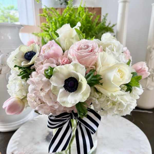Pink and white bouquet in a glass vase with a striped ribbon