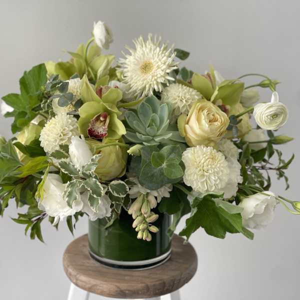 White and pale green floral arrangement in a green glass vase