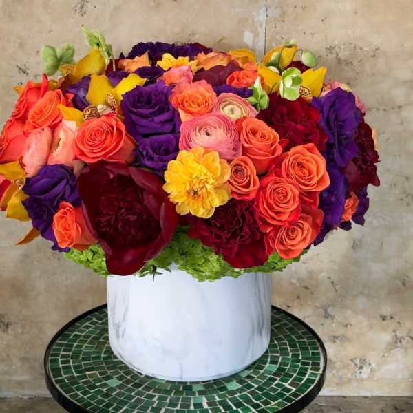 Bright mixed bouquet in a white vase with roses and ranunculus