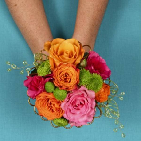 Handheld bouquet of orange, pink, and green flowers