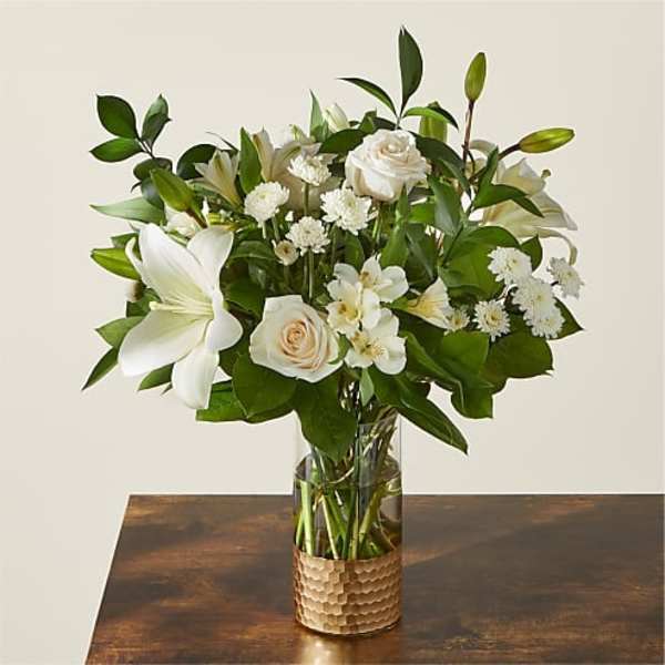White lilies and roses arranged in a glass vase