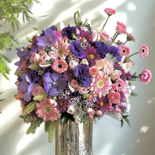 Large bouquet of pink, purple, and white flowers in a metallic vase