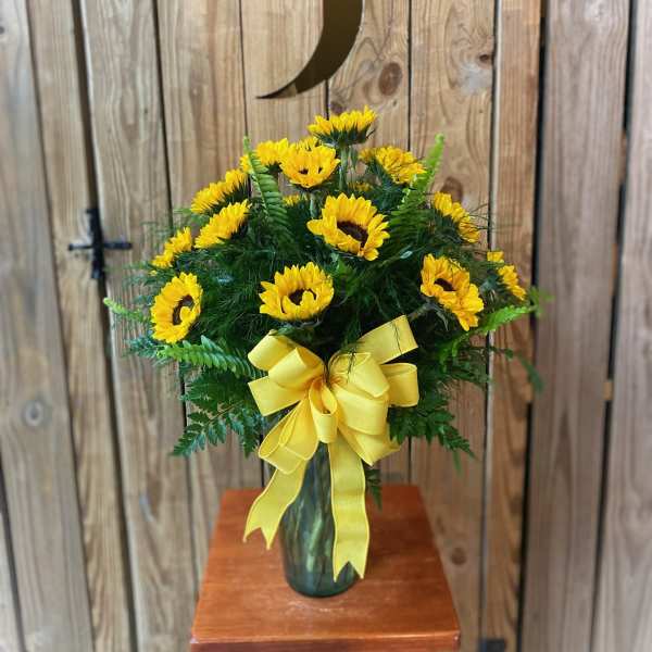 Yellow sunflower arrangement in a glass vase with a ribbon bow