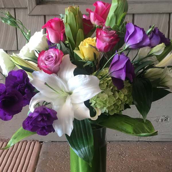 Mixed bouquet of roses, lilies, and hydrangea in a glass vase