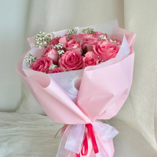 Pink rose bouquet wrapped in pale pink paper with a ribbon