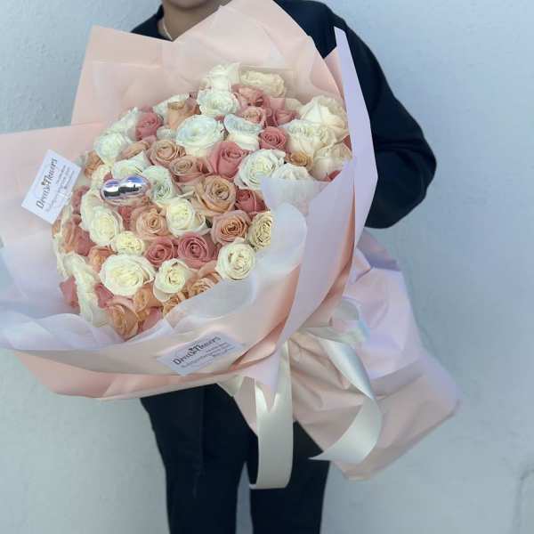 Large bouquet of blush and cream roses wrapped in pale pink paper