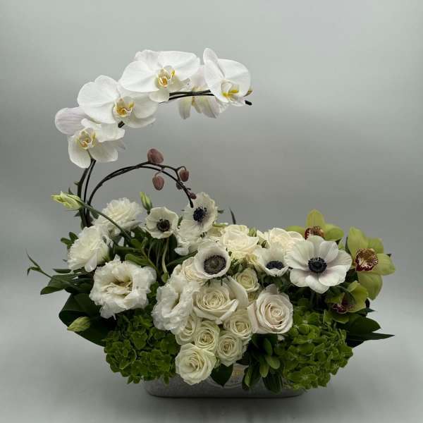 White orchids and roses arranged in a low rectangular container