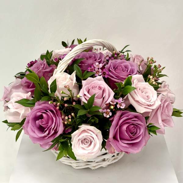 Basket of pink and lavender roses with small filler flowers