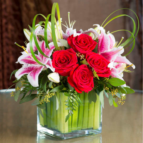 Red roses and pink lilies in a clear square vase