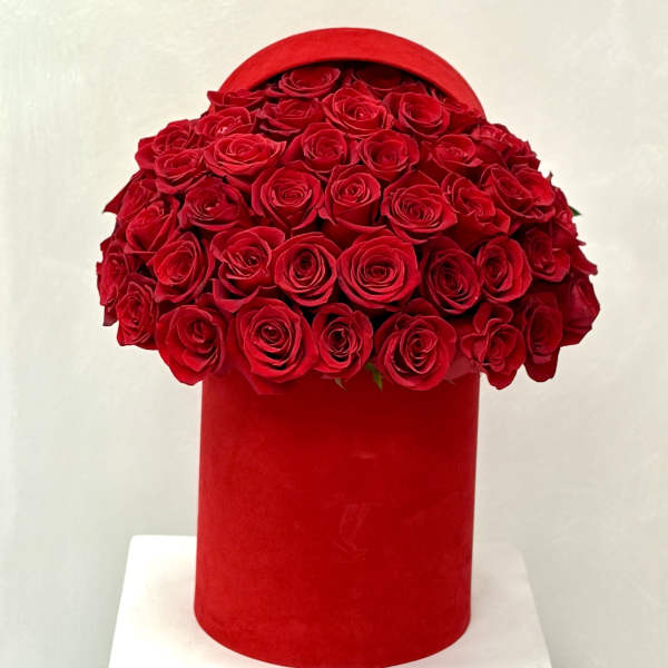 Red roses arranged in a round red hat box