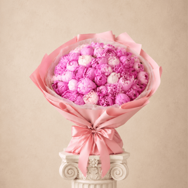 Pink bouquet of tightly packed blooms wrapped in satin ribbon