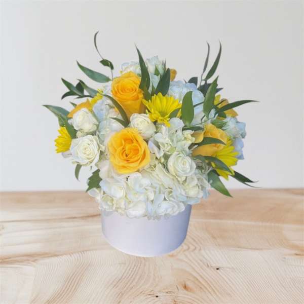 Yellow roses and white flowers in a white vase