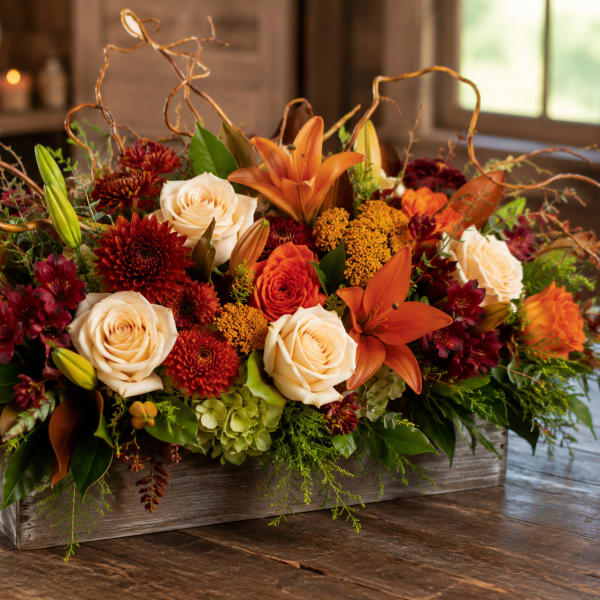 Autumn floral arrangement with roses, lilies, and mums in a wooden box
