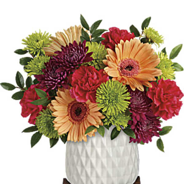 Colorful mixed flower arrangement in a white vase on a wooden stand