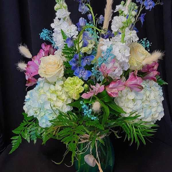 Mixed bouquet of pastel flowers in a dark vase