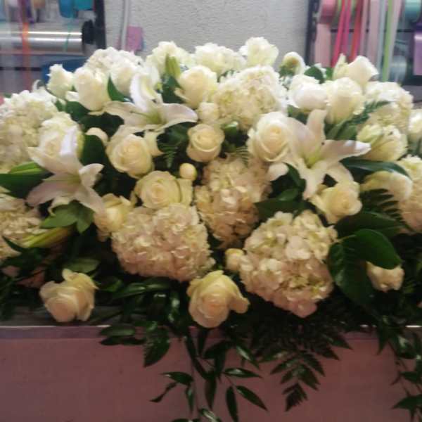 Large white floral arrangement with roses, lilies, and hydrangeas