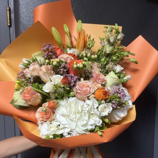 Bouquet of pink, white, and orange flowers wrapped in orange paper