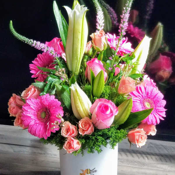 Pink and peach bouquet with lilies, roses, and gerbera daisies in a white vase