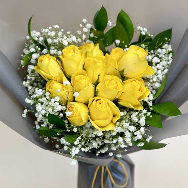 Bouquet of yellow roses with white baby's breath in gray wrapping