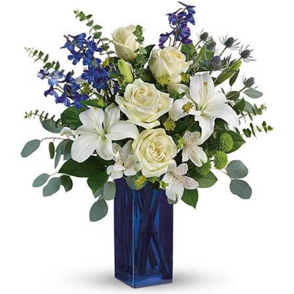 White roses and lilies with blue flowers in a tall blue vase