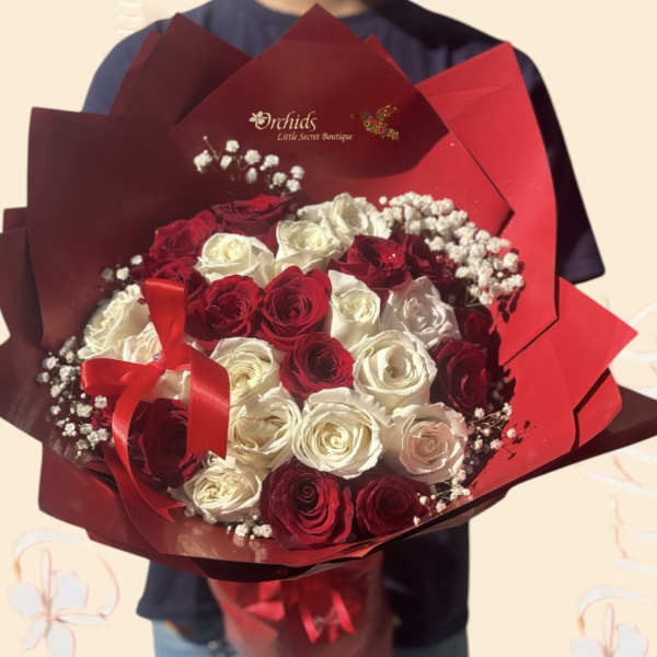Bouquet of red and white roses wrapped in red paper with a ribbon