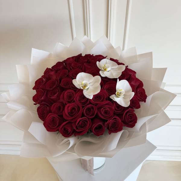 Bouquet of red roses with three white orchids wrapped in white paper