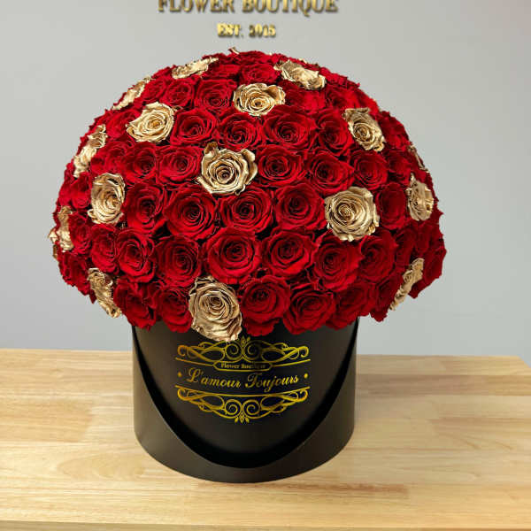 Round bouquet of red and gold roses in a black hatbox