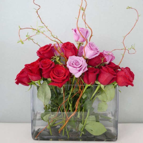 Red and pink roses arranged in a clear rectangular vase