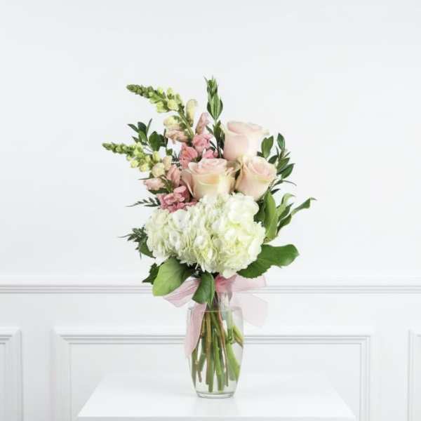 Bouquet of pale pink roses and white hydrangeas in a clear glass vase