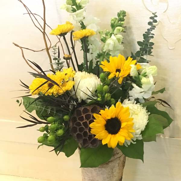Tall floral arrangement with yellow sunflowers and white blooms in a birch-style vase