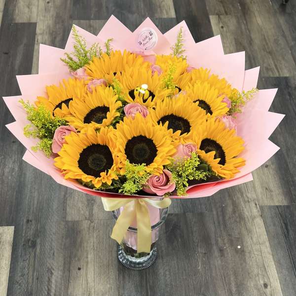 Bouquet of sunflowers and pink roses in a glass vase