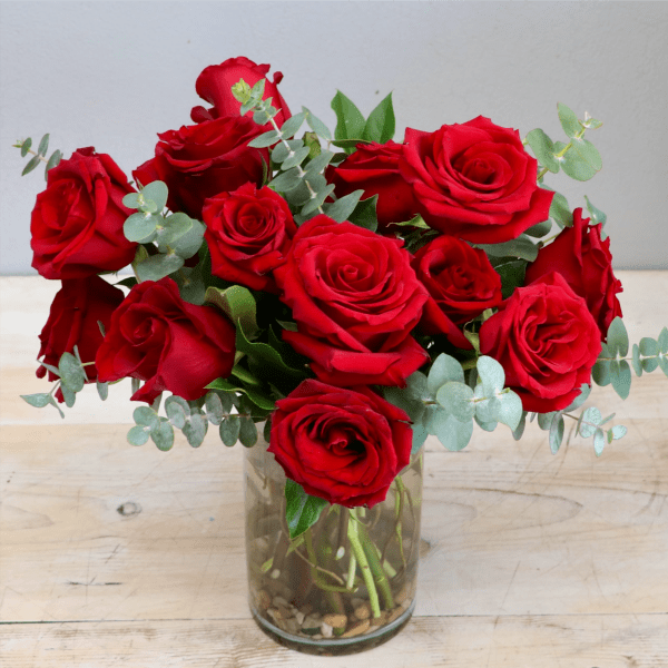 Arrangement of red roses with eucalyptus in a clear glass vase