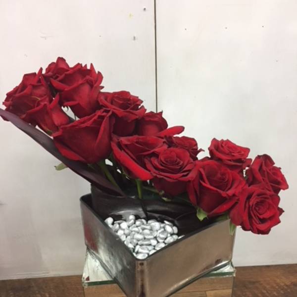 Red roses arranged in a square mirrored vase with silver stones
