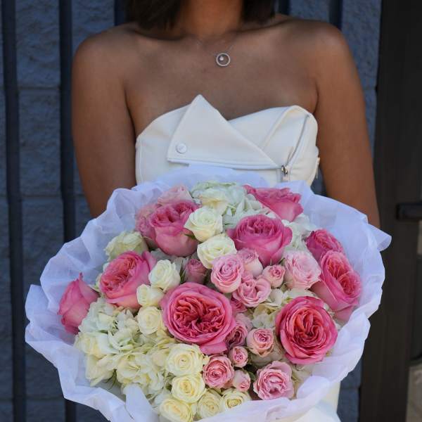 Large bouquet of pink and white roses wrapped in white paper