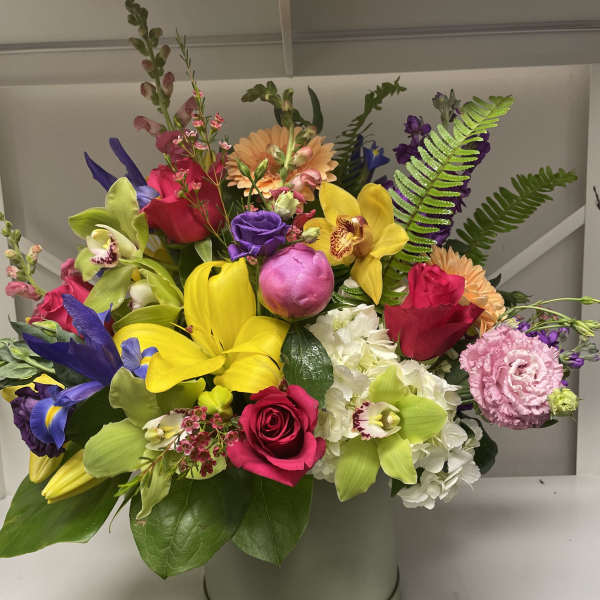 Bright mixed bouquet in a round hatbox with roses, orchids, lilies, and hydrangea