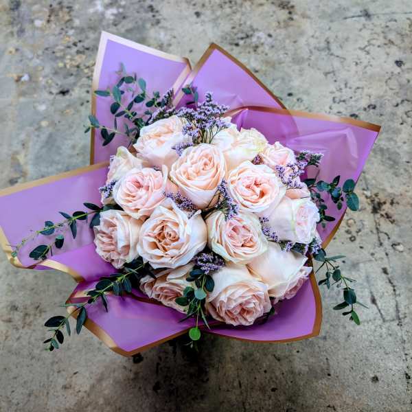 Bouquet of pale pink roses wrapped in purple paper