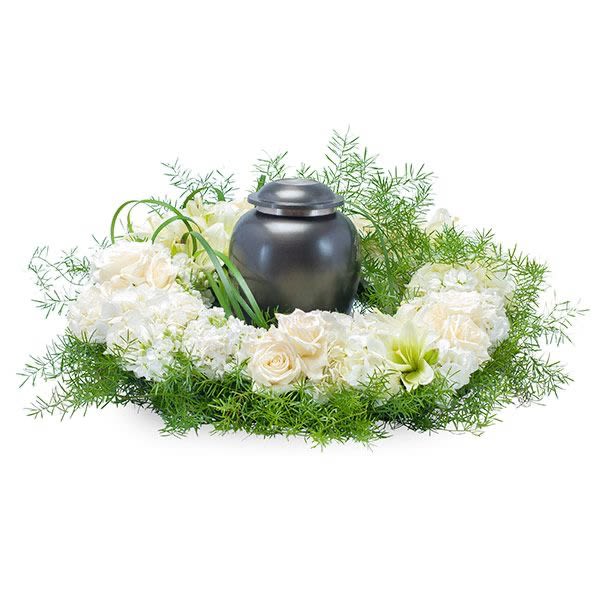 Cremation urn encircled by white roses and hydrangeas with green accents