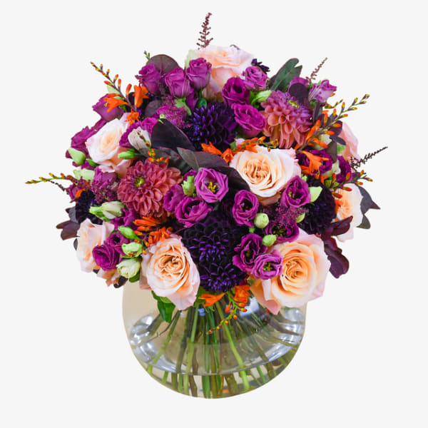 Bouquet of peach and purple flowers in a clear glass vase