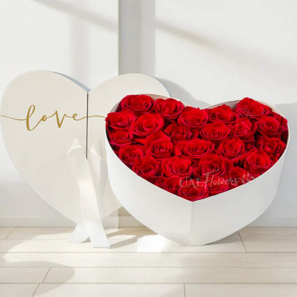 Heart-shaped box filled with red roses beside a matching heart lid