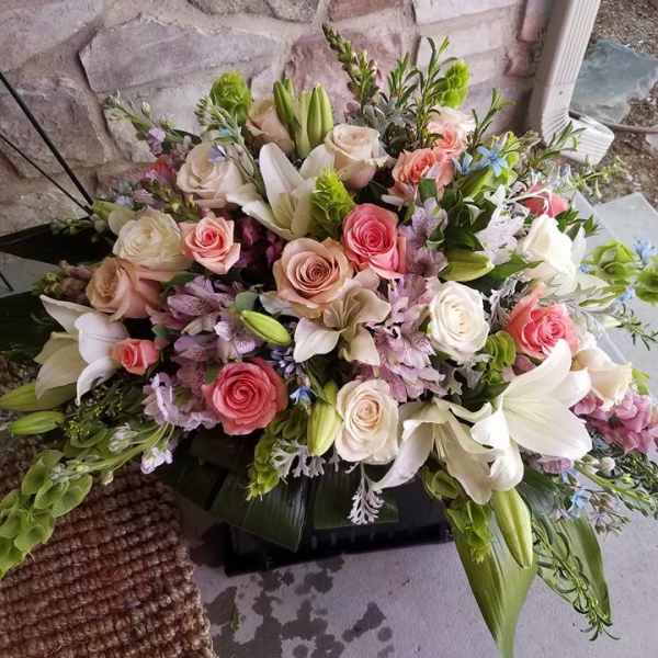 Large floral arrangement with roses and lilies in pink, white, and lavender