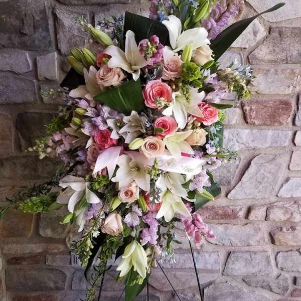 Tall standing floral spray with white lilies, pink roses, and lavender blooms