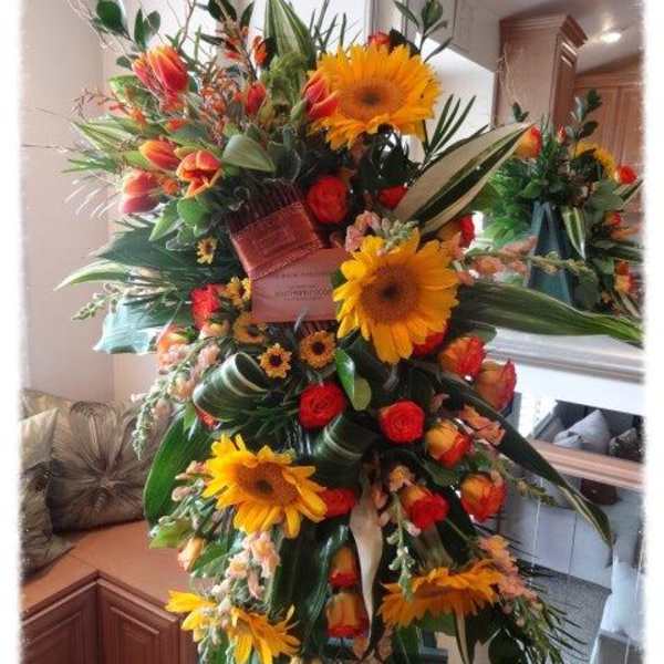Large standing floral arrangement with sunflowers and red-orange roses