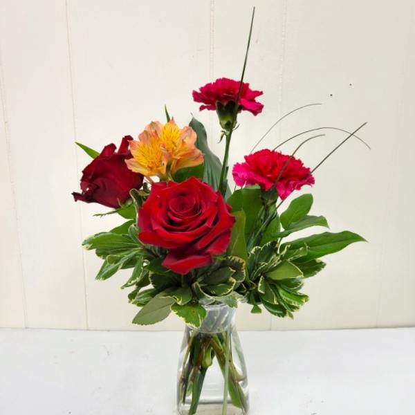 Mixed bouquet of red roses and pink carnations in a clear glass vase