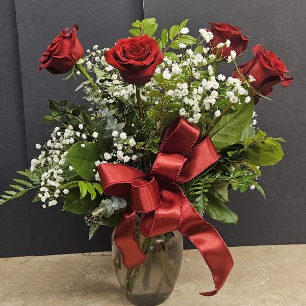 Red roses with baby's breath in a glass vase and red ribbon