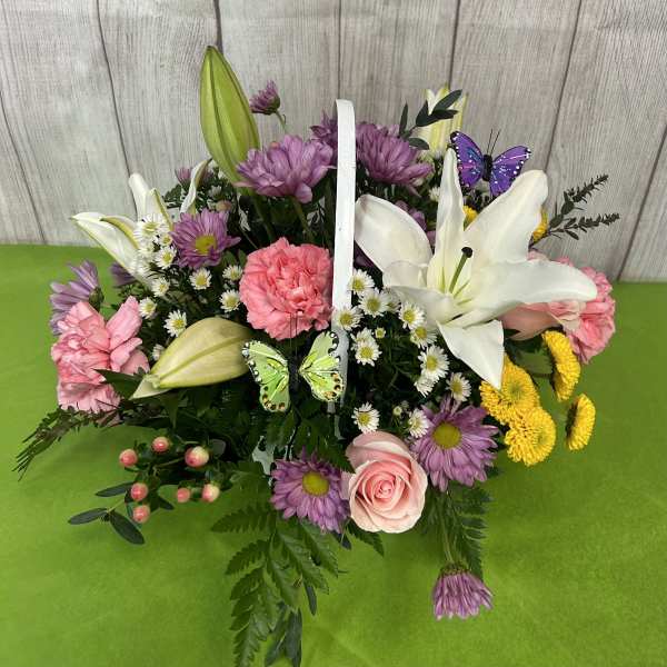Basket arrangement with lilies, pink carnations, purple daisies, and butterflies