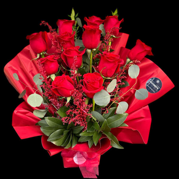 Bouquet of red roses wrapped in red paper with greenery
