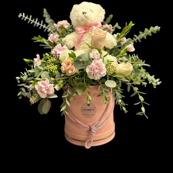 Pink and cream floral arrangement in a peach hatbox with a teddy bear