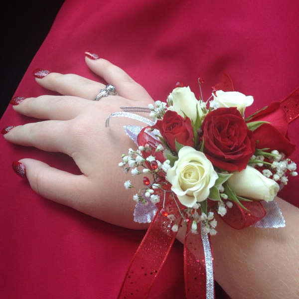 Hand corsage with red and white roses on a red dress