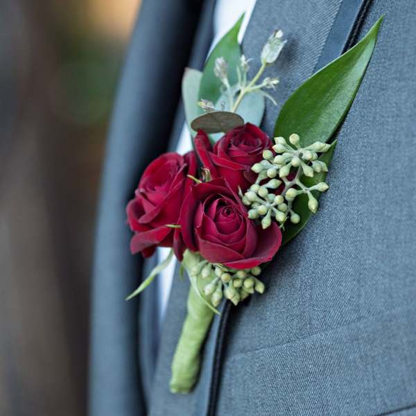 Red rose boutonniere pinned to a gray suit jacket