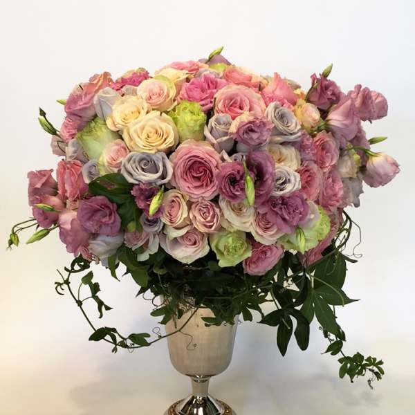 Large pastel rose arrangement in a silver pedestal vase